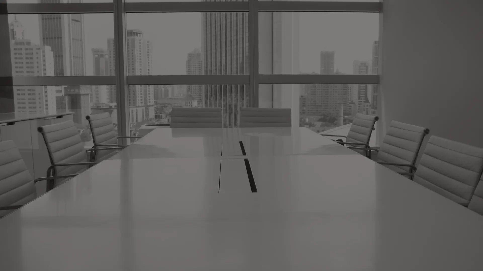 A boardroom with a white table and nine white chairs lining the table.