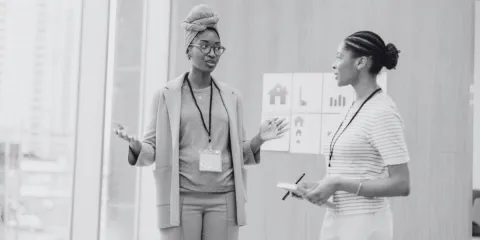 Two people are walking side-by-side in an office space conversing.